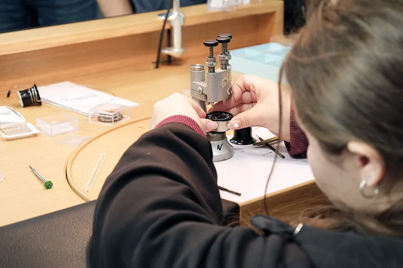 Jeune fille s'essayant &agrave; l'horlogerie lors d'un salon des m&eacute;tiers en Suisse romande